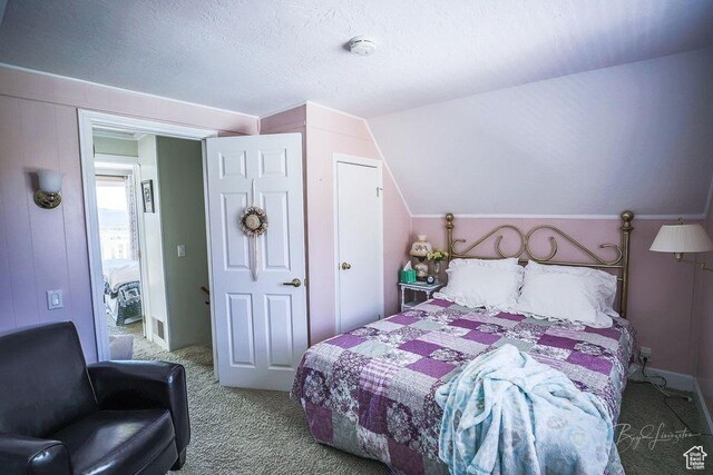 carpeted bedroom with vaulted ceiling and a textured ceiling