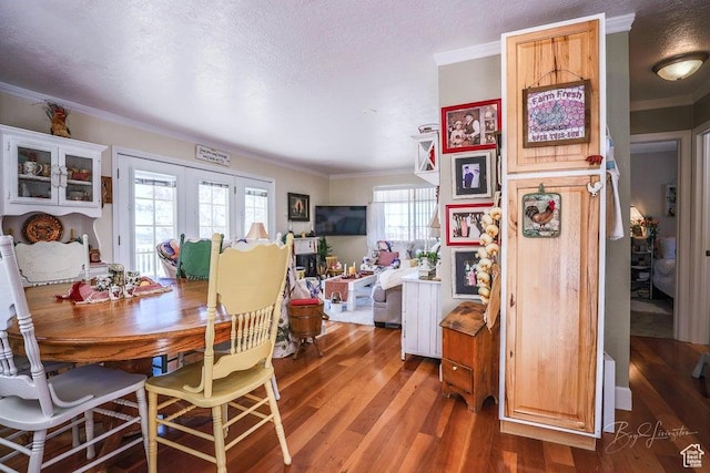 dining space featuring crown molding, a textured ceiling, and wood finished floors