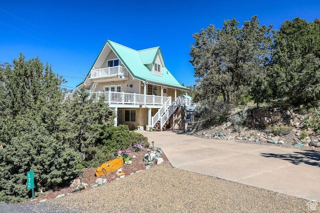 view of front of property with stairs, concrete driveway, a porch, and a balcony