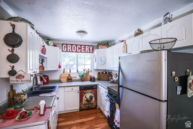 kitchen with freestanding refrigerator, a sink, dishwasher, and white cabinets