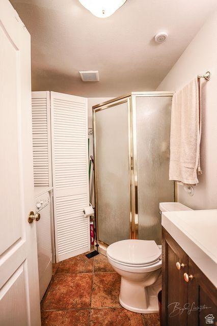 bathroom featuring vanity, toilet, tile patterned flooring, and a stall shower