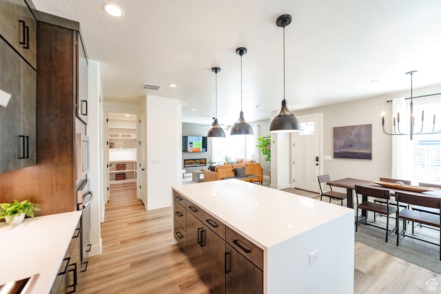 7093 W Granbury Dr S Unit 255, South Jordan, UT 84009 - kitchen with a center island, light wood-style flooring, a chandelier, and dark brown cabinets