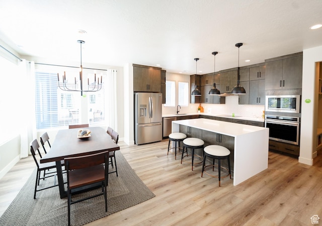 7093 W Granbury Dr S Unit 255, South Jordan, UT 84009 - kitchen with a kitchen island, a kitchen breakfast bar, a sink, a notable chandelier, and stainless steel appliances