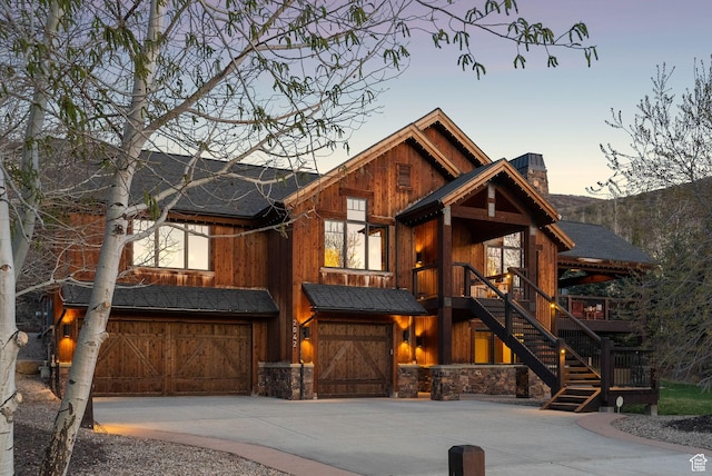 2042 Paddington Dr, Park City, UT 84060 - rustic home featuring an attached garage, stone siding, concrete driveway, stairway, and a chimney