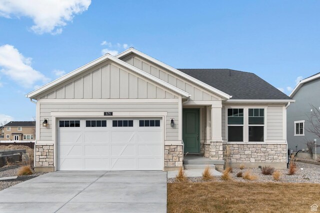 craftsman house with board and batten siding, driveway, stone siding, and a garage