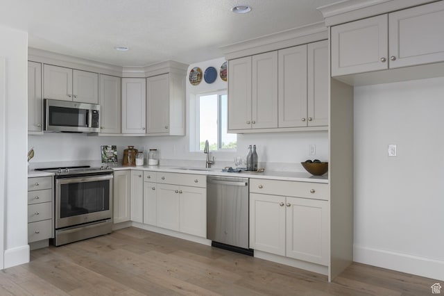 1478 W 400 N, West Bountiful, UT 84087 - kitchen featuring appliances with stainless steel finishes, a sink, baseboards, light countertops, and light wood finished floors