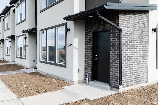 doorway to property featuring stucco siding and brick siding