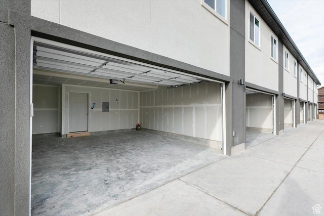 garage with a garage door opener, driveway, and electric panel