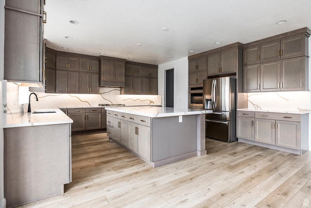 5081 W Sequoia Cir, Highland, UT 84003 - kitchen featuring a center island, a sink, light wood finished floors, backsplash, and stainless steel appliances