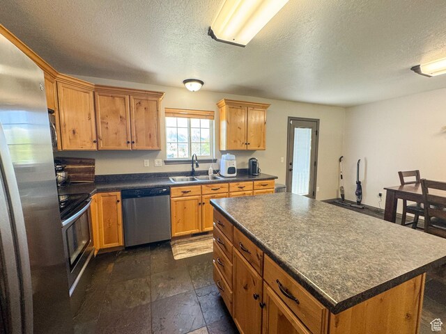 3261 S 1500 W, Nibley, UT 84321 - kitchen featuring dark countertops, a center island, a textured ceiling, a sink, and stainless steel appliances