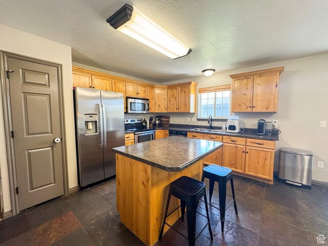 3261 S 1500 W, Nibley, UT 84321 - kitchen featuring dark countertops, a center island, stainless steel appliances, stone finish flooring, and a kitchen bar