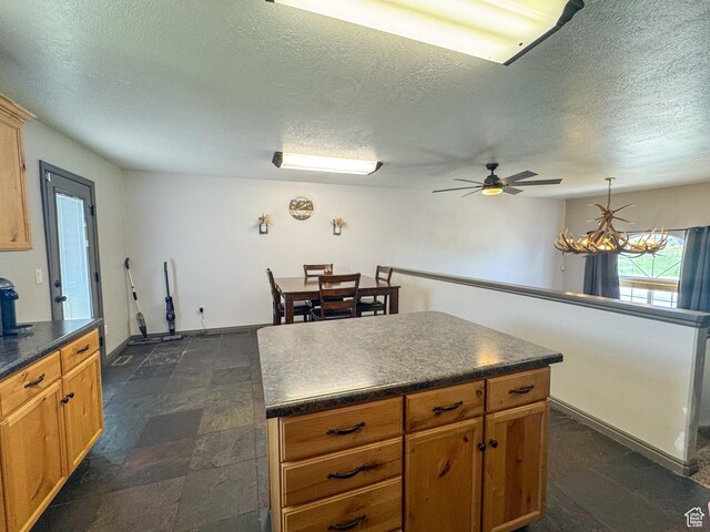 3261 S 1500 W, Nibley, UT 84321 - kitchen with a textured ceiling, ceiling fan, a kitchen island, and dark countertops