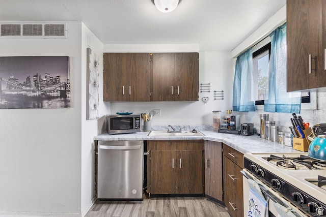 472 E Marva Ave, Layton, UT 84041 - kitchen with appliances with stainless steel finishes, a sink, light countertops, light wood-style flooring, and dark brown cabinets