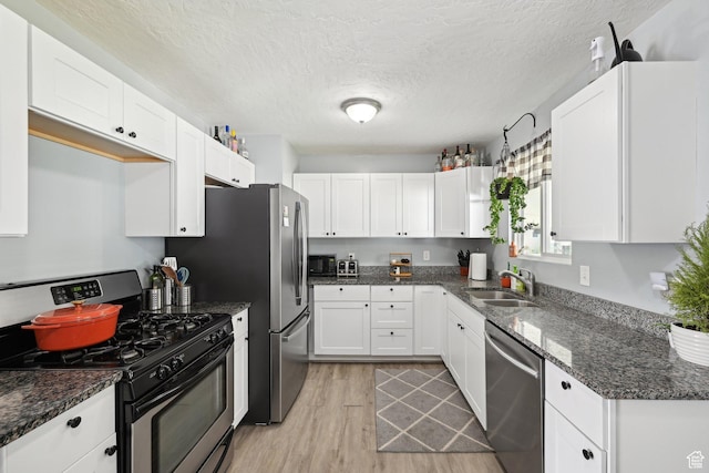 293 E Valley View Dr, Tooele, UT 84074 - kitchen featuring white cabinets, appliances with stainless steel finishes, a sink, light wood-style floors, and dark stone countertops