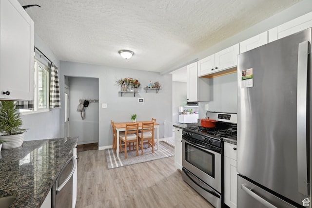 293 E Valley View Dr, Tooele, UT 84074 - kitchen with white cabinets, a textured ceiling, dark stone counters, stainless steel appliances, and light wood-type flooring