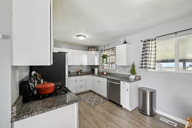 293 E Valley View Dr, Tooele, UT 84074 - kitchen featuring visible vents, white cabinetry, a sink, light wood-style flooring, and stainless steel appliances