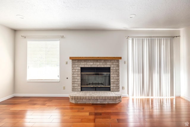 176 N 170 E, Orem, UT 84057 - unfurnished living room with baseboards, a textured ceiling, wood finished floors, and a fireplace