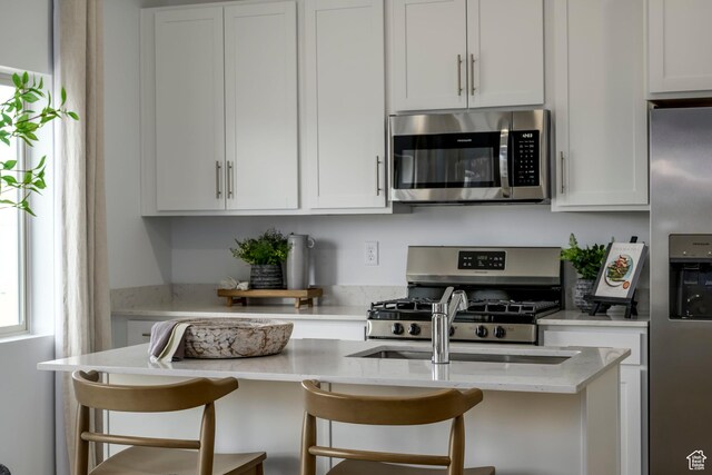 141 N Gallery St, Saratoga Springs, UT 84045 - kitchen with appliances with stainless steel finishes, white cabinets, and a breakfast bar area