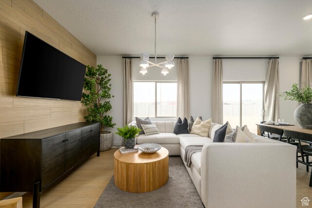 141 N Gallery St, Saratoga Springs, UT 84045 - living room featuring a healthy amount of sunlight, light wood-style floors, a textured ceiling, and a notable chandelier