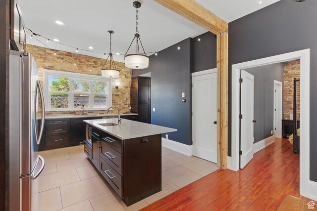 775 E Simpson Ave, Salt Lake City, UT 84106 - kitchen with dark brown cabinetry, a sink, light countertops, freestanding refrigerator, and a center island with sink