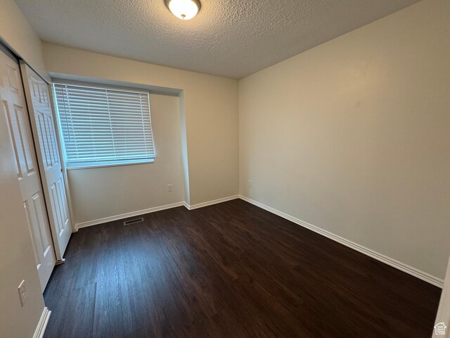 1952 E Sunset Dr, Layton, UT 84040 - unfurnished bedroom with visible vents, a closet, baseboards, dark wood-style floors, and a textured ceiling