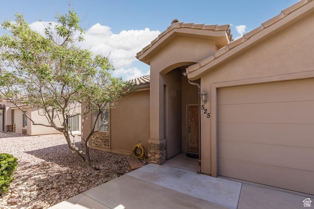 view of exterior entry with a garage and stucco siding