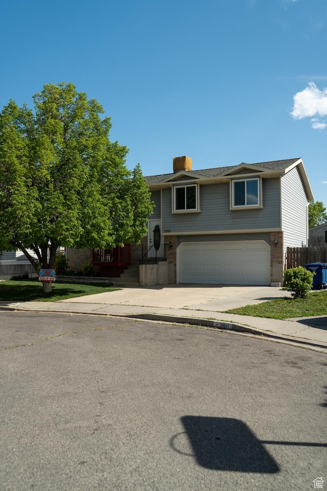 3505 W San Marcos Cir, West Valley City, UT 84119 - bi-level home with a garage, fence, concrete driveway, and brick siding
