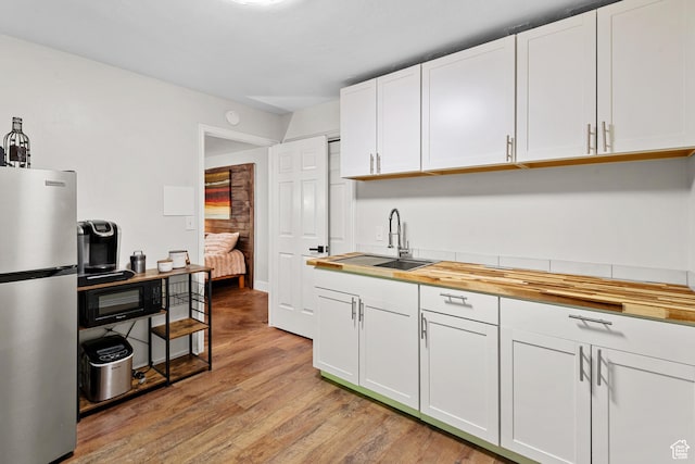 11622 S Worthington Ct E, Sandy, UT 84092 - kitchen with freestanding refrigerator, a sink, butcher block countertops, light wood-style floors, and white cabinetry