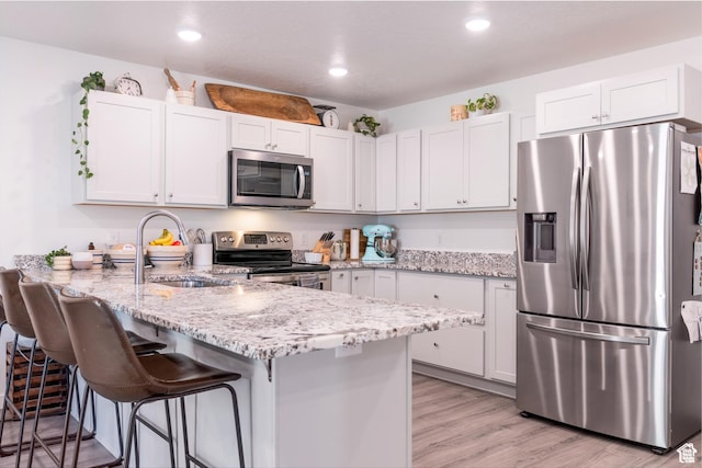 375 N 700 W, Vernal, UT 84078 - kitchen with light stone countertops, appliances with stainless steel finishes, a sink, light wood-style floors, and a peninsula