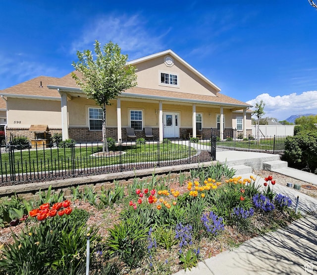 country-style home with fence private yard, a front lawn, stucco siding, and stone siding