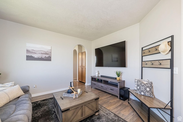 6709 S Empress Ln W, West Jordan, UT 84081 - living room featuring arched walkways, baseboards, a textured ceiling, and wood finished floors