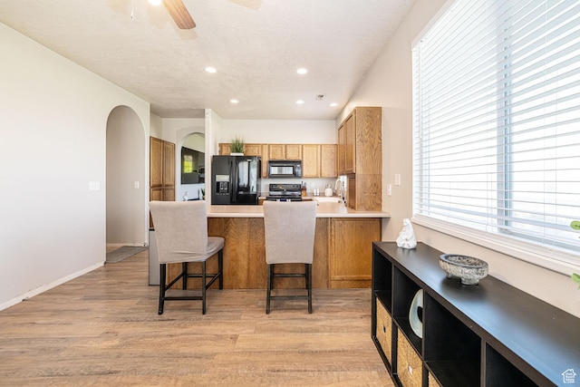 6709 S Empress Ln W, West Jordan, UT 84081 - kitchen with light wood-style floors, arched walkways, a peninsula, and black appliances