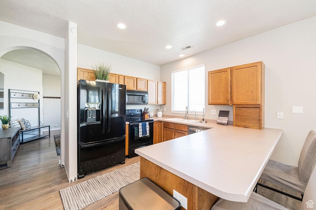 6709 S Empress Ln W, West Jordan, UT 84081 - kitchen with a peninsula, visible vents, a kitchen breakfast bar, and black appliances