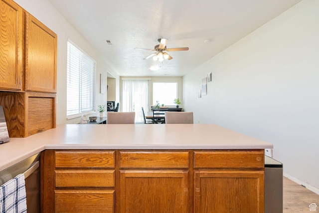 6709 S Empress Ln W, West Jordan, UT 84081 - kitchen featuring brown cabinetry, a peninsula, light countertops, a ceiling fan, and light wood-style flooring