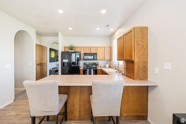 6709 S Empress Ln W, West Jordan, UT 84081 - kitchen featuring a sink, light countertops, arched walkways, a peninsula, and black appliances