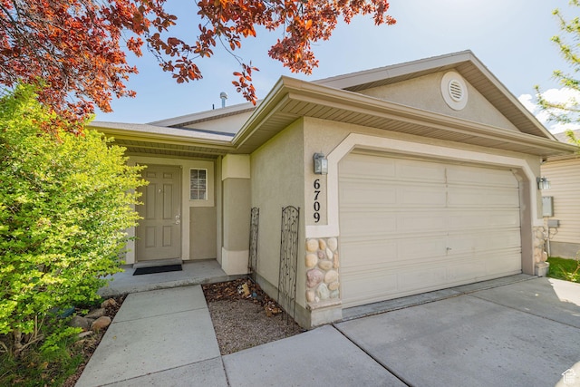 6709 S Empress Ln W, West Jordan, UT 84081 - view of front of house with a garage, stucco siding, driveway, and stone siding