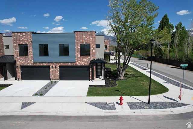 contemporary home featuring an attached garage, brick siding, and concrete driveway