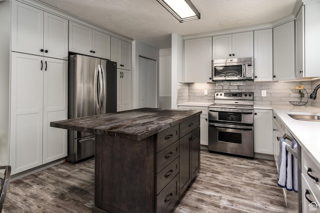 9745 S Tayside Dr W, South Jordan, UT 84009 - kitchen with appliances with stainless steel finishes, a sink, wood finished floors, tasteful backsplash, and a textured ceiling
