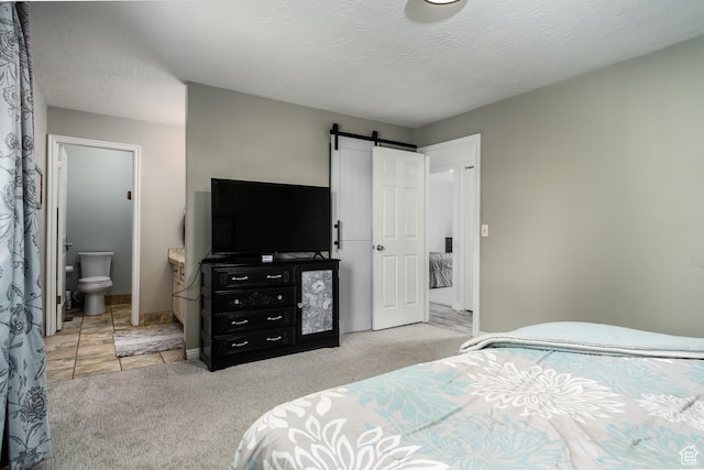 9745 S Tayside Dr W, South Jordan, UT 84009 - bedroom with a barn door, carpet flooring, ensuite bath, a textured ceiling, and baseboards