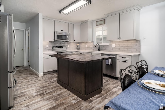 9745 S Tayside Dr W, South Jordan, UT 84009 - kitchen with stainless steel appliances, butcher block countertops, light wood-style floors, backsplash, and a sink