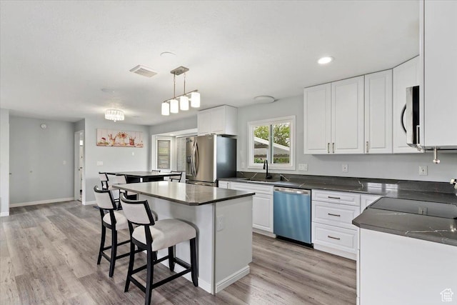 4612 S 600 E, Murray, UT 84107 - kitchen with a kitchen breakfast bar, appliances with stainless steel finishes, a center island, a sink, and white cabinetry