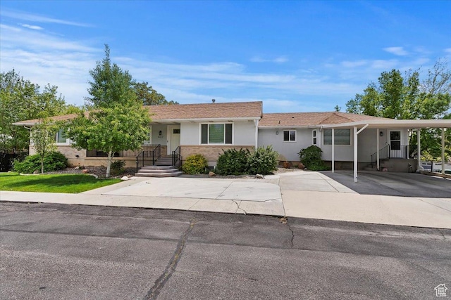 ranch-style home with stucco siding, driveway, and a carport