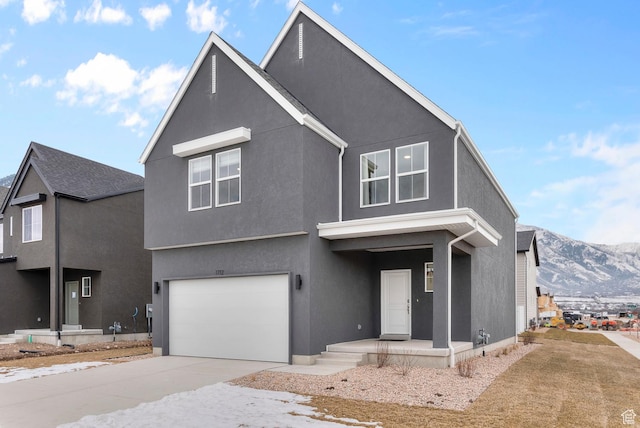view of front of property with a mountain view, an attached garage, concrete driveway, and stucco siding