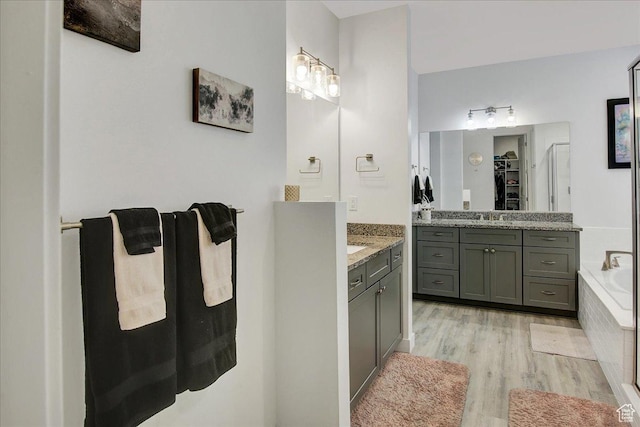 6264 W Antelope Flat Way S, Herriman, UT 84096 - bathroom with tiled bath, a walk in closet, a sink, two vanities, and wood finished floors