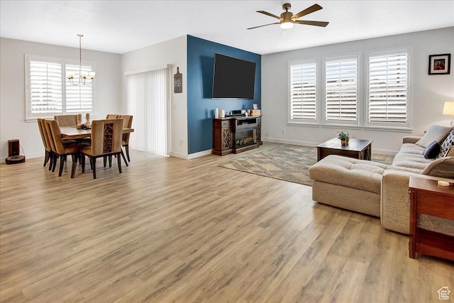 6264 W Antelope Flat Way S, Herriman, UT 84096 - living room featuring baseboards, light wood finished floors, ceiling fan with notable chandelier, and a wealth of natural light