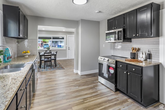 987 S Jefferson Ave E, Ogden, UT 84404 - kitchen with light wood-style floors, a sink, dark cabinetry, and appliances with stainless steel finishes