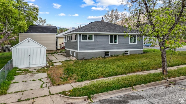 987 S Jefferson Ave E, Ogden, UT 84404 - view of home's exterior featuring a storage shed, a lawn, an outbuilding, and a shingled roof
