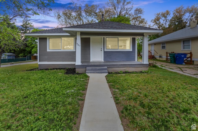 bungalow-style home featuring a porch, a shingled roof, and a front lawn