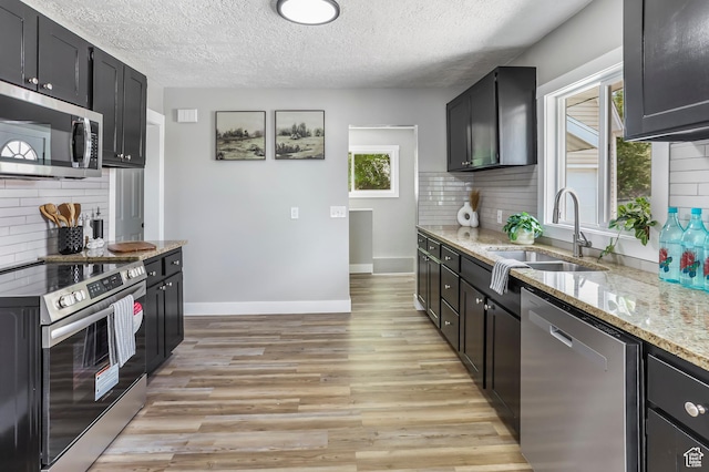 987 S Jefferson Ave E, Ogden, UT 84404 - kitchen with decorative backsplash, a textured ceiling, a sink, light stone counters, and stainless steel appliances