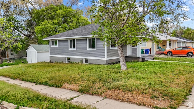 987 S Jefferson Ave E, Ogden, UT 84404 - view of front of home with fence, a front yard, roof with shingles, a storage unit, and an outbuilding
